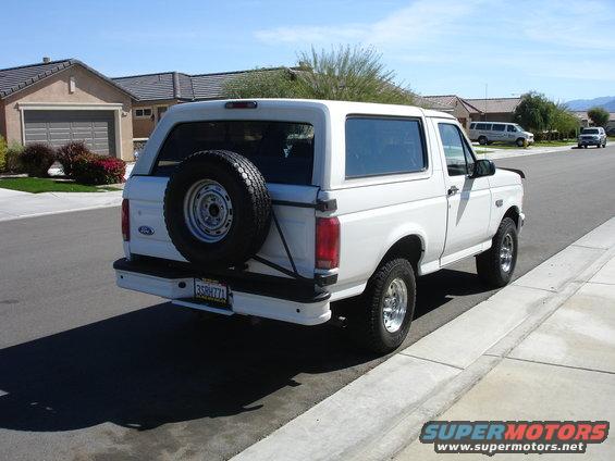 White Ford Bronco parked on a suburban street, spare tire mounted on the back. License plate reads 35BHH771