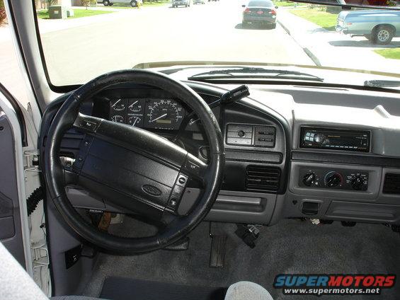 dashboard and steering wheel of a truck, looking out at a street with other cars