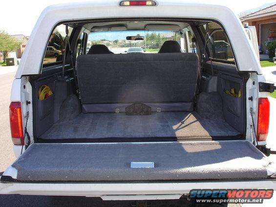 Rear cargo area of a white Ford Bronco, showing folded down rear seats and storage compartments
