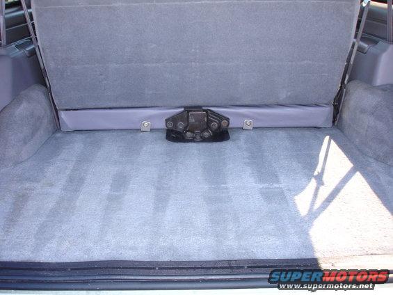 Gray carpeted cargo area with folded rear seat and black latch mechanism