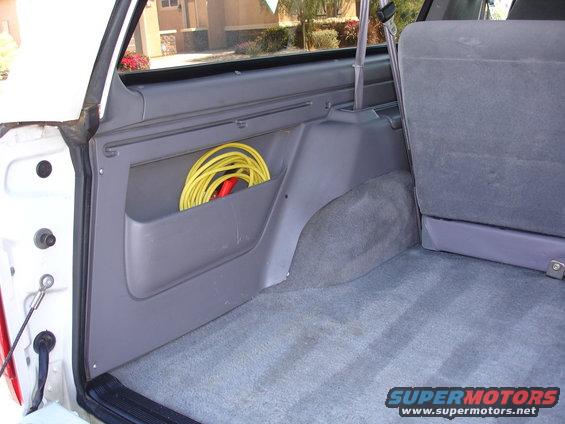 Interior cargo area of a vehicle with a yellow cord coiled in a side pocket