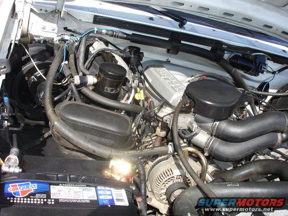 Engine bay of a 1996 Ford Bronco, showing the V8 engine, battery, and various hoses and wires