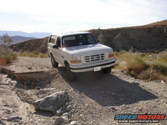 White 1996 Ford Bronco on a dirt road in a desert landscape