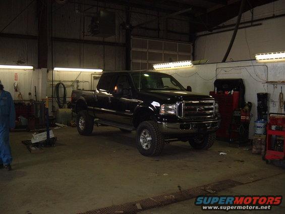 Black pickup truck parked in a garage, front 3/4 view
