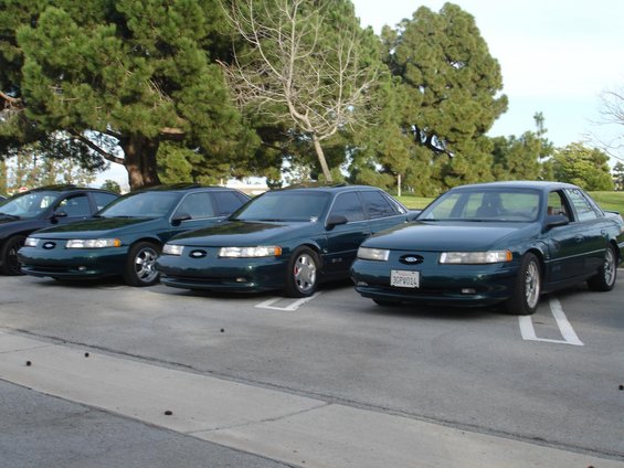 Three dark green 1993 Ford Tauruses parked side-by-side, front view