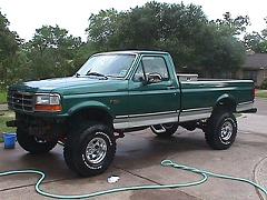 Green 1992 Ford F-150 pickup truck with lifted suspension and aftermarket wheels