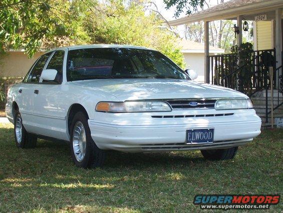 White Ford Crown Victoria parked on grass in front of a house