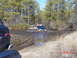 1995 Dodge 1500 - Multiple vehicles navigate a muddy water crossing on a wooded trail, kicking up water and mud.