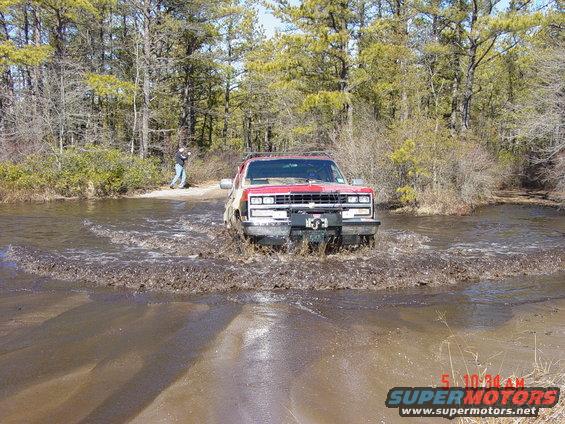 Red 1995 Chevrolet K1500 driving through mud