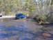 1995 Dodge 1500 - A black SUV is stuck in a muddy water crossing, with trees and brush surrounding the area.