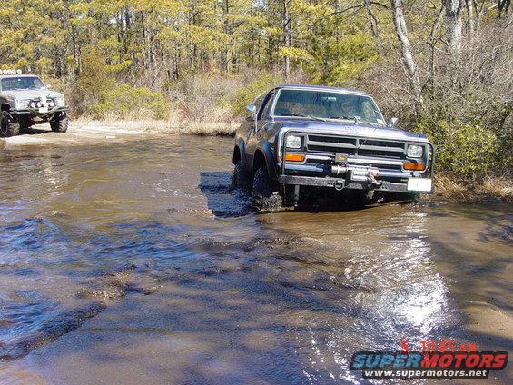 Dark blue Dodge Ram pickup truck with a winch on the front bumper driving through shallow water