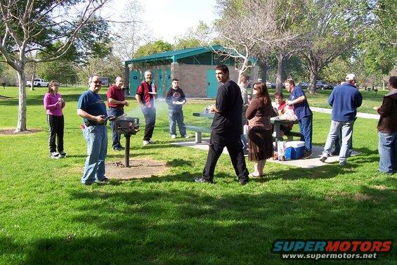 People gathered in a park for a barbecue with grills and picnic tables