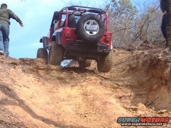 Red Jeep Wrangler climbing a steep dirt hill. License plate Y44-VPO visible