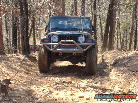 Front view of a dark blue 2004 Jeep TJ navigating a rocky trail