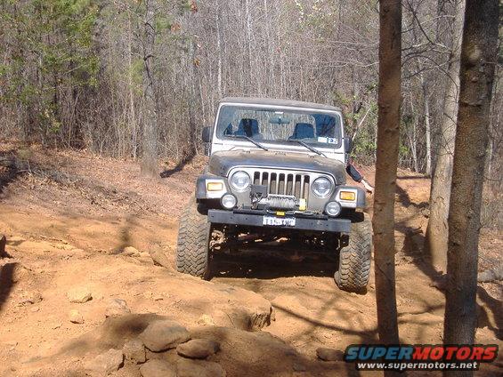 Silver Jeep TJ with winch on front bumper navigating rocky terrain