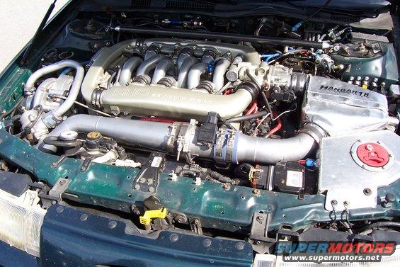 Green engine bay with V6 engine, silver intake pipes, and "Hangar18" label on a silver cover