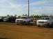1996 Ford Bronco - Three Ford Broncos are parked on a dirt lot under a bright blue sky.
