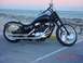 1989 Ford Bronco - A black motorcycle with custom chrome wheels is parked near the water on a paved surface.