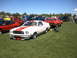 1978 Ford Mustang II - White 1978 Ford Mustang II Cobra II with red stripes is parked on grass at a car show with other vehicles.