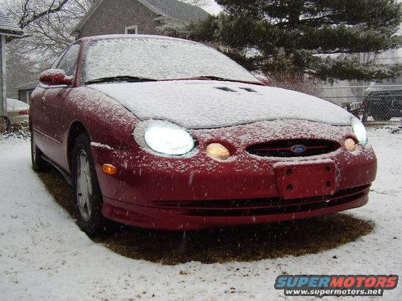 Red Ford Taurus with snow on hood and windshield, front view