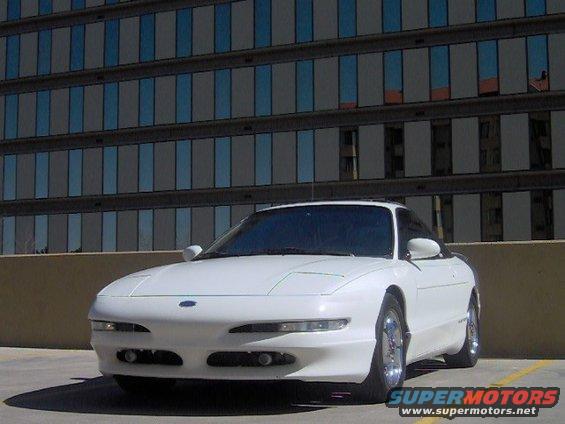 White 1996 Ford Probe coupe parked in front of a modern building