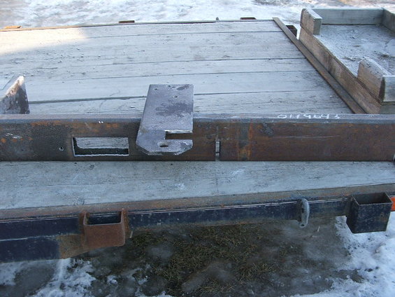 Trailer frame with a metal bracket attached. Stamped numbers visible on frame