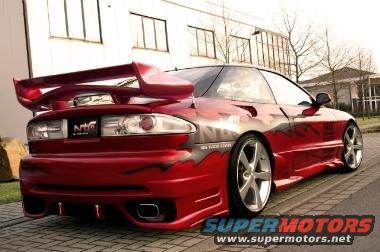 Red sports car with custom body kit and large rear spoiler parked on pavement