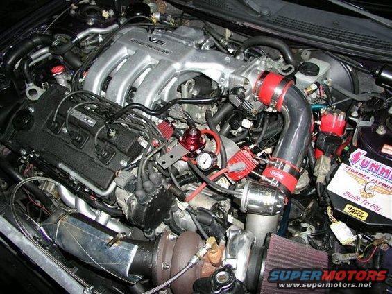 Engine bay with V6 engine, turbocharger, red fuel pressure regulator, and Summit Racing parts box