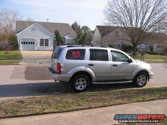 Silver 2005 Dodge Durango parked on street with a red Dodge logo sticker on rear window