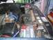 1986 Ford Bronco - The engine bay of a vehicle, an Interstate battery and various hoses and components.