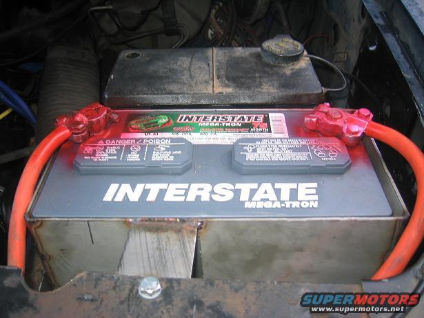 Interstate Mega-Tron car battery with red cables and a metal bracket