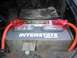 1986 Ford Bronco - A car battery with red cables and a metal bracket is visible in the engine bay.