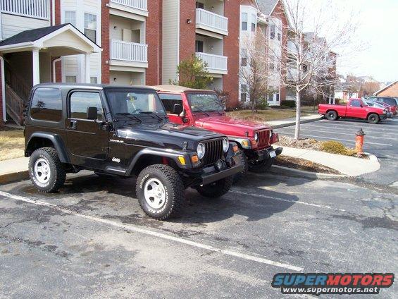 Black Jeep Wrangler parked next to a red Jeep Wrangler in a parking lot