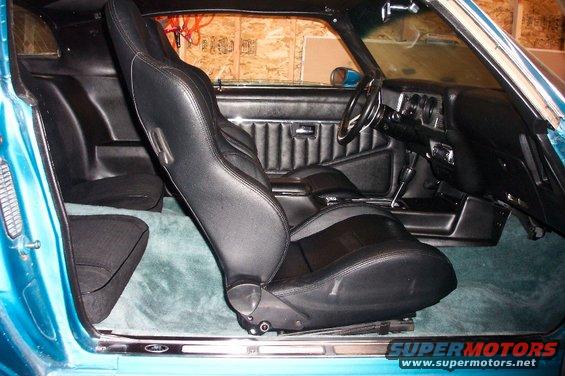 Interior of a 1979 Pontiac Trans Am with black bucket seats and teal carpet