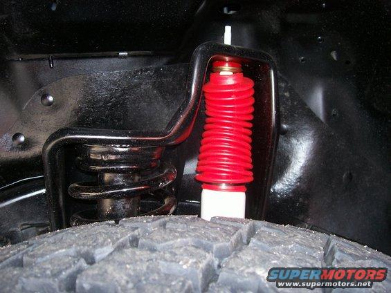 Close-up of red coilover shock absorber and black spring assembly above tire tread