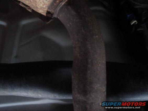 Close-up of a rusty exhaust pipe under a vehicle