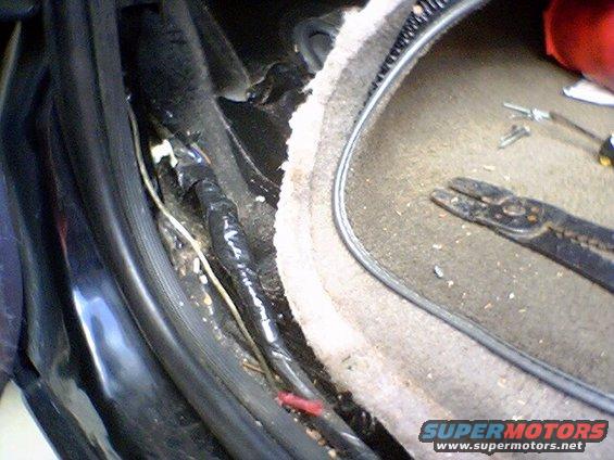 Close-up of vehicle interior wiring with electrical tape and wire strippers nearby