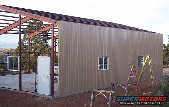 Construction site with a partially built metal building, ladders, and a door