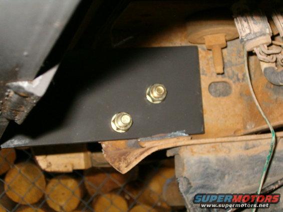 Black metal bracket bolted to rusty frame