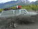 1990 Chevrolet Suburban - A 1990 Chevrolet Suburban kicks up mud as it drives through a muddy terrain with mountains in the background.