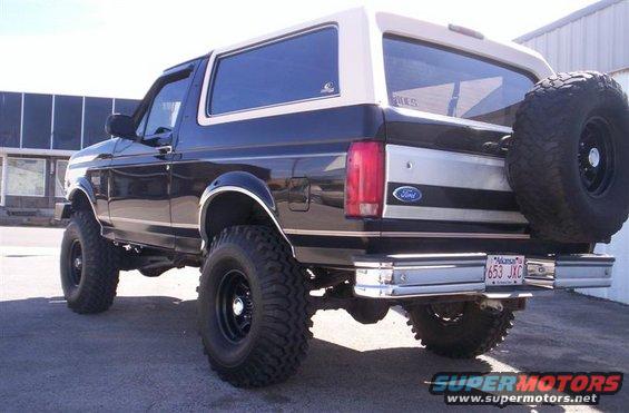Black Ford Bronco with tan top, lifted with large tires, spare tire on back. License plate 653 JXC
