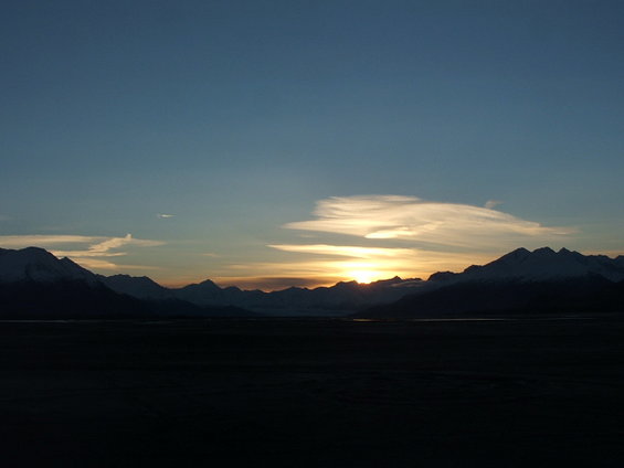 Mountain range silhouetted against a sunset sky with clouds