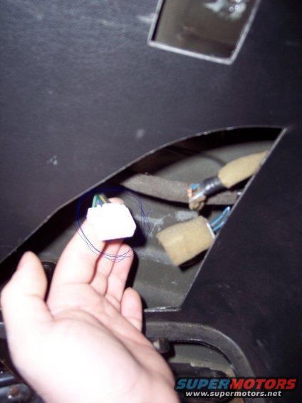 Hand holding a white wiring harness connector with blue and green wires