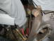 1979 Ford Bronco - Close-up of corroded vehicle components and electrical wiring, with a partial view of a person's legs.