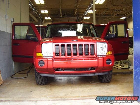Red Jeep Commander with doors open, parked indoors