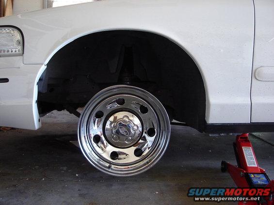 2000 Ford Crown Victoria front wheel removed, showing chrome hubcap with Ford logo