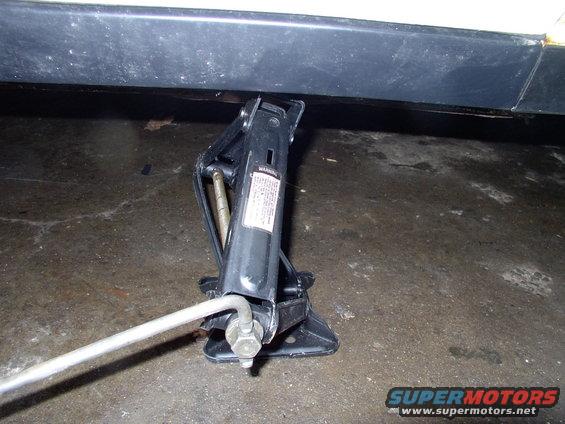 Car jack positioned under the rocker panel of a vehicle