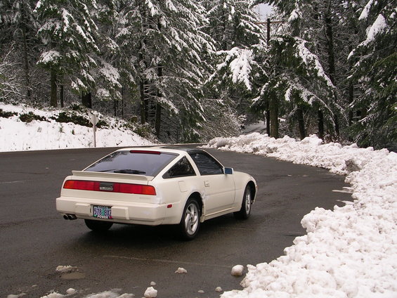 White 1989 Nissan 300ZX on a wet road with snow on the sides and trees