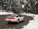 1989 Nissan 300ZX - A white 1989 Nissan 300ZX drives on a wet road surrounded by snow-covered trees.