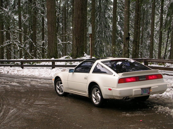 1989 Nissan 300ZX parked on a wet road with snow and trees in the background